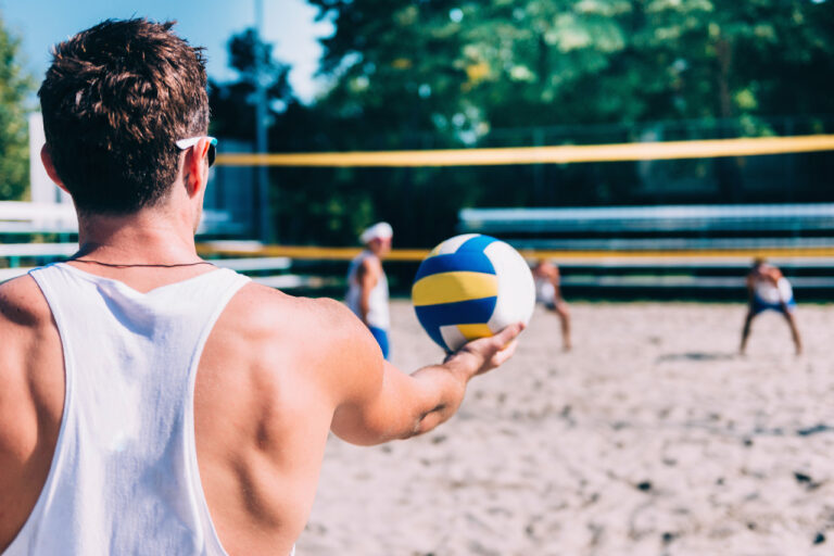 a man serving in beach volleyball