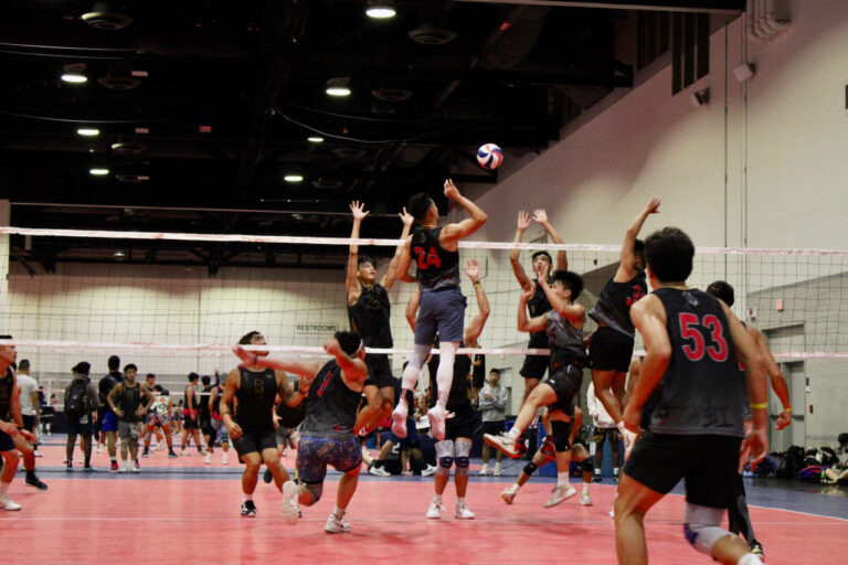 three volleyball players in the air attacking the ball