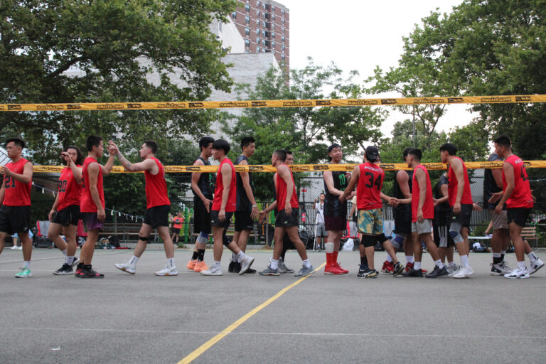 a group of guys walking across a volleyball net shaking hands