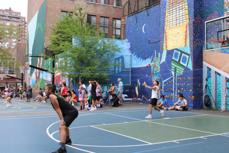 a guy serving a volleyball in a colorful playground area